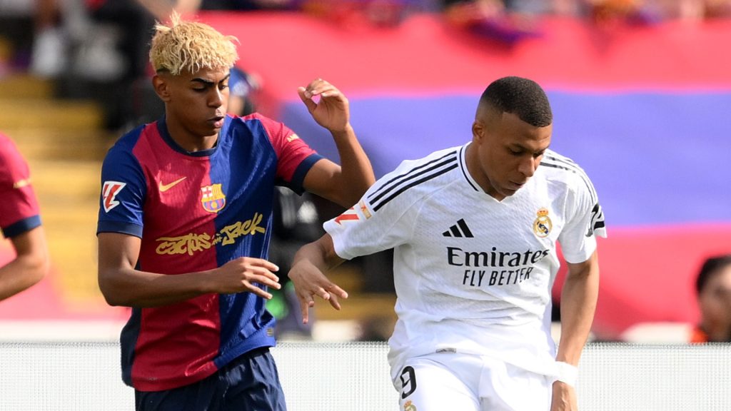 Kylian Mbappe of Real Madrid passes the ball under pressure from Lamine Yamal of FC Barcelona during the LaLiga match between FC Barcelona and Real Madrid CF at Estadi Olimpic Lluis Companys on May 11, 2025 in Barcelona, Spain.